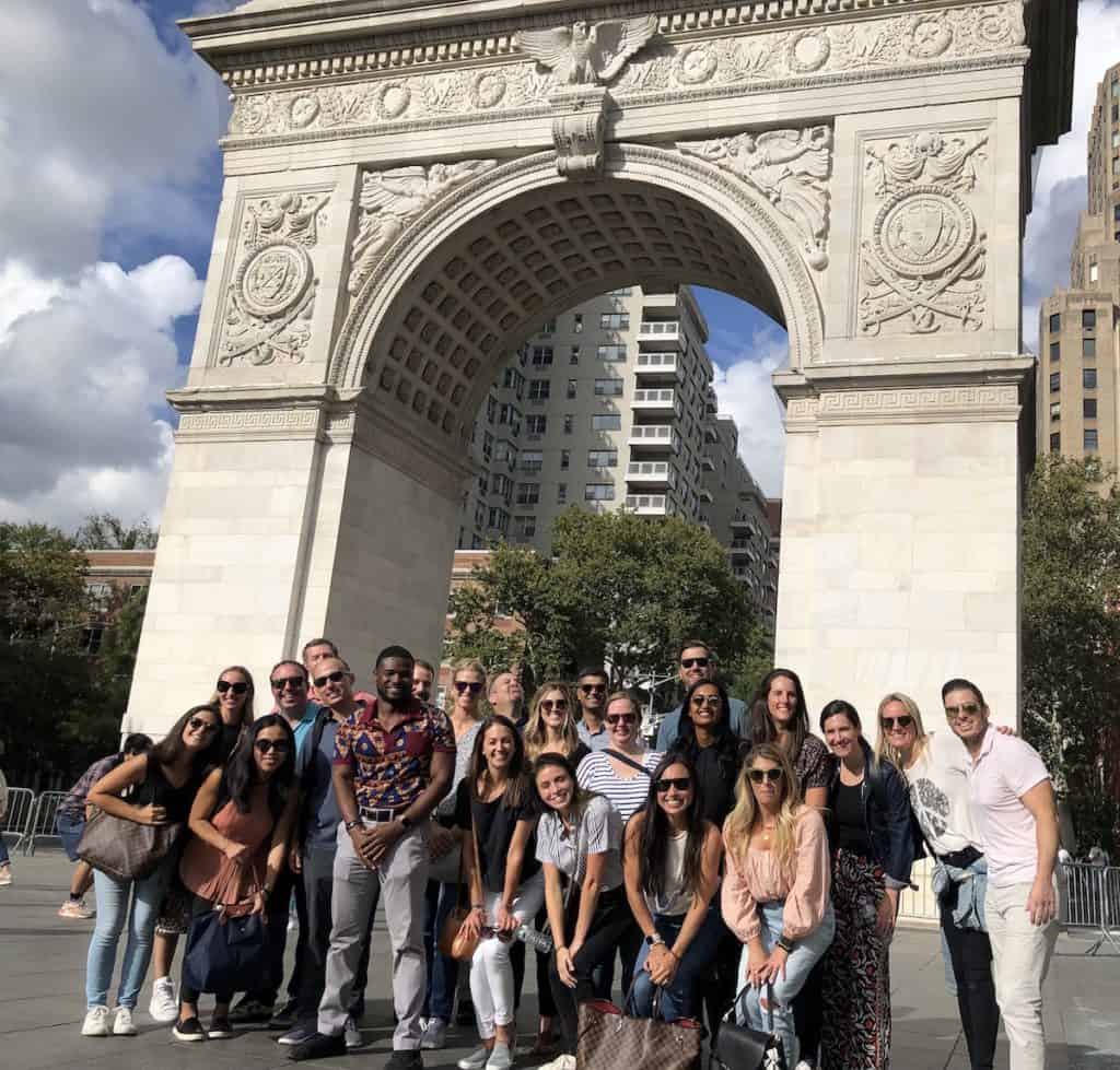 Corporate team posing beneath the Washington Square Arch during a Washington Square Park scavenger hunt team building event in NYC
