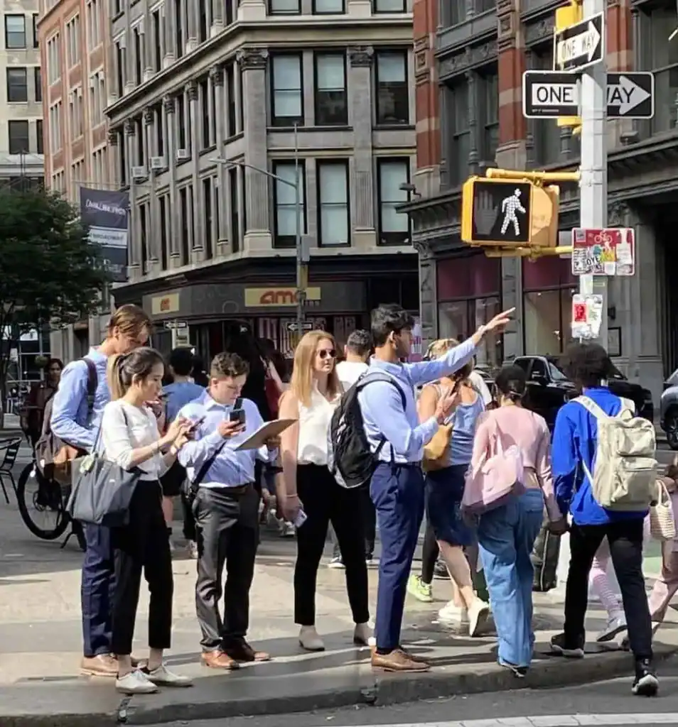 Team solving clues at crosswalk in Flatiron District near Madison Square Park during NYC scavenger hunt